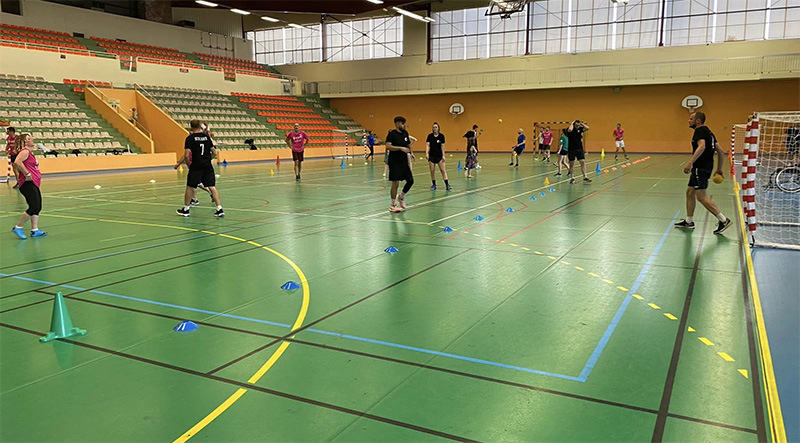 Tournoi inter entreprises dans le gymnase : Photo de personnes jouant au handball avec des exercices ludiques